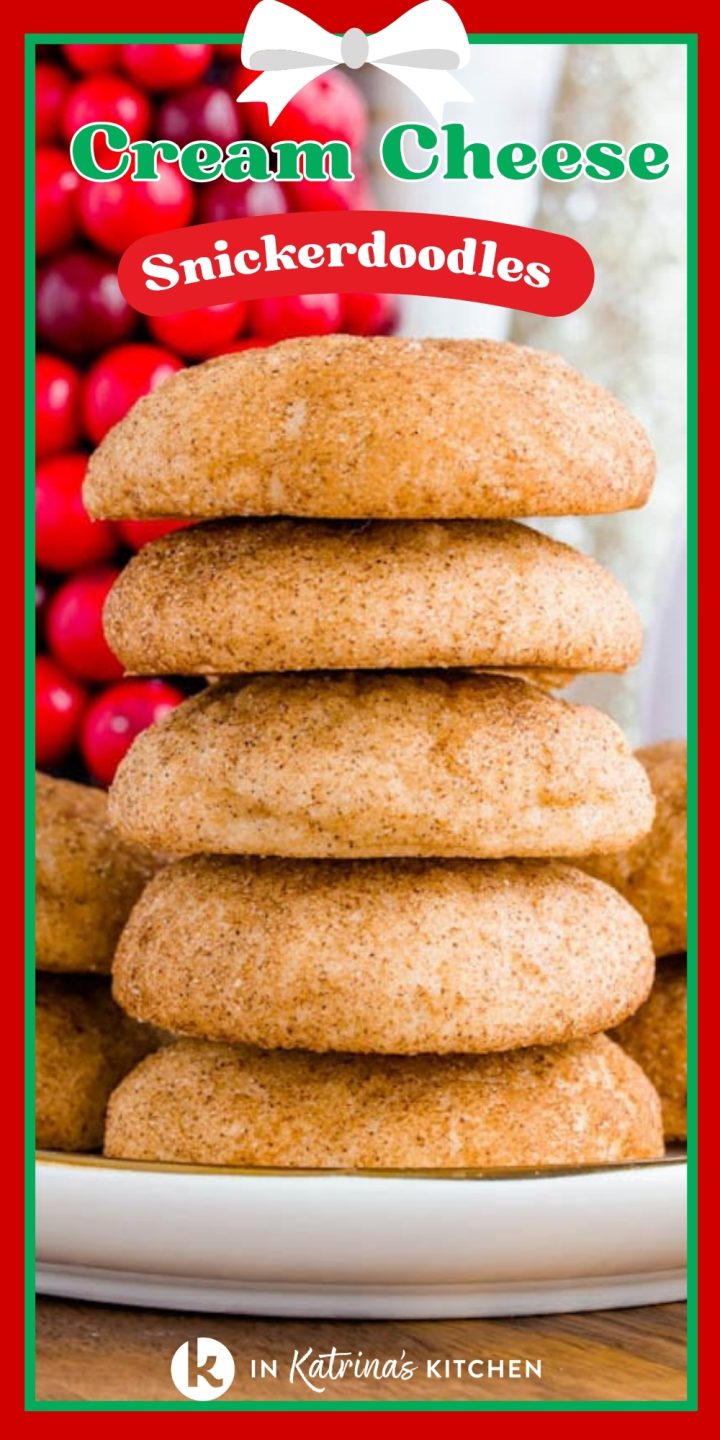 A vertical photo featuring a tall stack of four thick, cinnamon-sugar-dusted snickerdoodle cookies on a white plate. In the background are vibrant red berries, and at the top of the image, green and red text framed by a white ribbon bow reads "Cream Cheese Snickerdoodles."